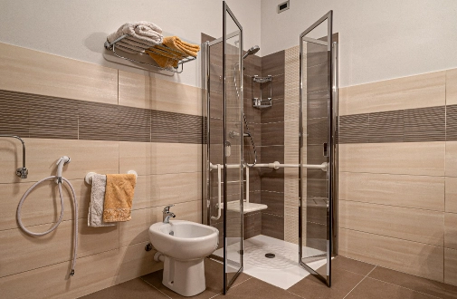 foto secondaria del bagno in camera Azalea che mostra un bidet e la doccia attrezzata anche per persone con difficoltà motorie